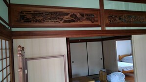 Ett traditionellt japanskt rum med skjutdörrar, ett golv av tatamimattor och ett lågt tak av trä.