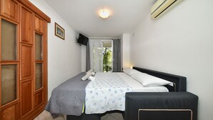 A bedroom with a bed, a chair, a wardrobe, a TV, and an air conditioner. - Apartment 1099/9469 (Istria - Rovinj), 400m from the beach (Rovinj)