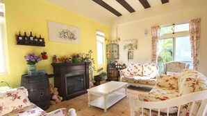 A cozy living room with a fireplace, floral furniture, and a yellow wall. - Provence Villa (Nanzhuang)