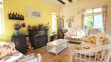A cozy living room with a fireplace, floral furniture, and a yellow wall.