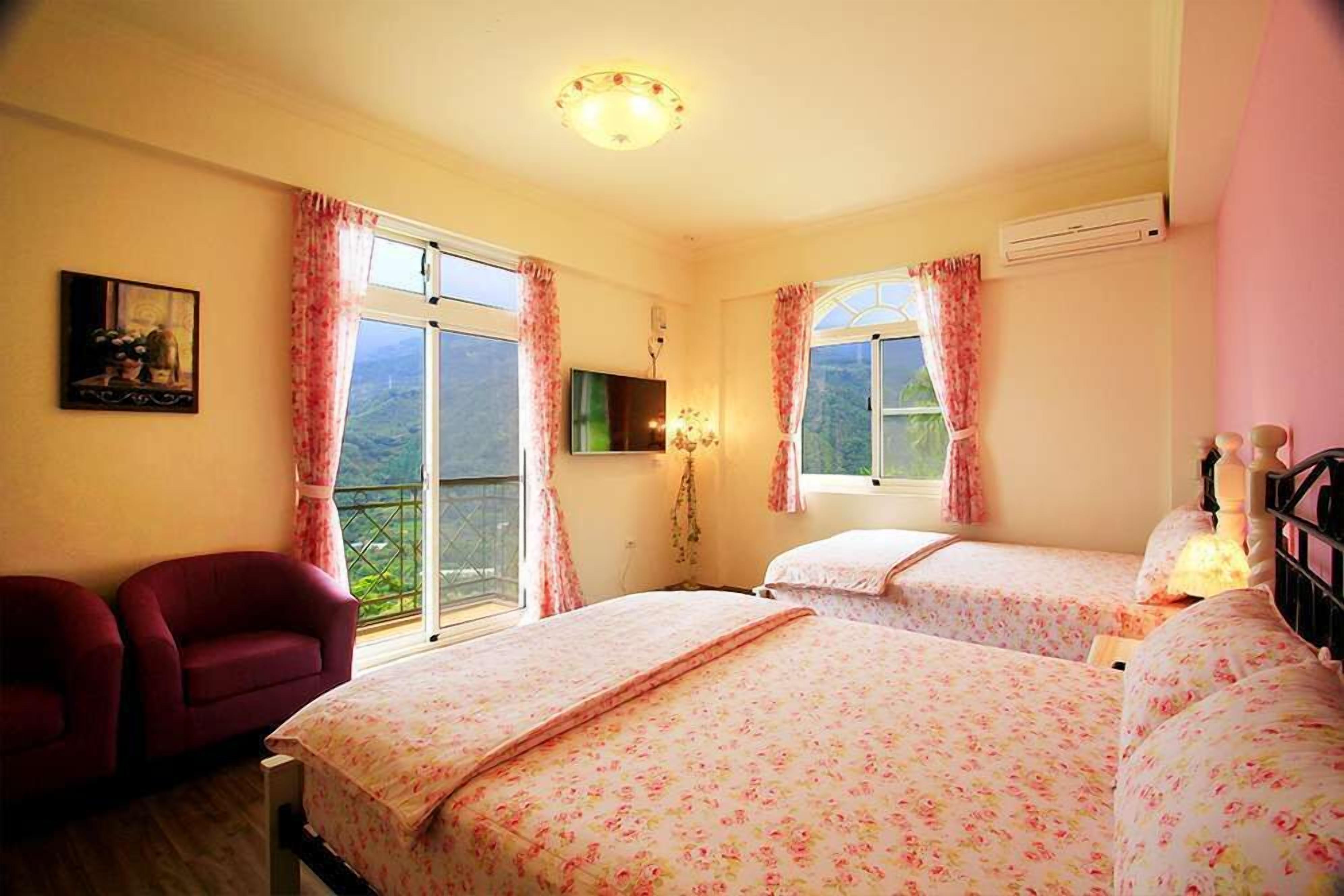 A hotel room with two beds, a TV, a chair, and a balcony with a view.