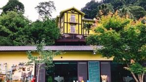 A yellow building with a balcony, surrounded by greenery and a small garden. - Provence Villa (Nanzhuang)