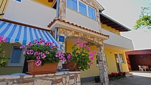 A two-story building with a stone facade, a blue and white striped awning, and potted pink flowers in front. - Apartment 1112/9595 (Istria - Fažana), 350m from the beach (Fažana)