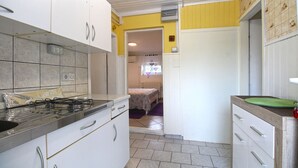 A compact kitchen with white cabinets, a gas stove, and a small window. - Apartment 1112/9595 (Istria - Fažana), 350m from the beach (Fažana)
