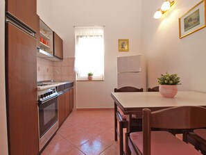 A compact kitchen with a stove, oven, and a dining table with chairs. - Apartment 1124/9663 (Istria - Valbandon), 500m from the beach (Valbandon)