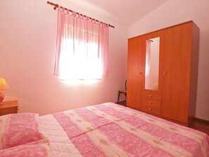 A bedroom with a bed, a wooden wardrobe, a chair, and a window with curtains. - Apartment 1124/9663 (Istria - Valbandon), 500m from the beach (Valbandon)