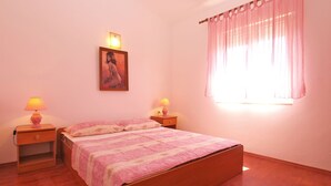 Ein Schlafzimmer mit einem hölzernen Bett, zwei Nachttischlampen, einem Gemälde an der Wand und einem Fenster mit Vorhängen.