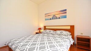 Une chambre à coucher avec un lit, une table de chevet, une lampe, un tableau au mur et une étagère en bois.
