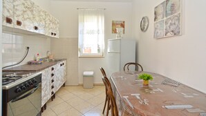 Une cuisine compacte équipée d’une cuisinière, d’un évier et d’un réfrigérateur. On y trouve une table à manger avec des chaises et une petite plante en pot.