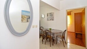 Un coin repas avec une table ronde, des chaises, une horloge et des œuvres d’art murales.