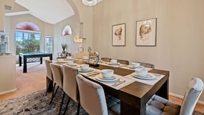 A dining area with a long table set for six, surrounded by cushioned chairs. A pool table is visible in the background. - LAS VEGAS LUXURY HOME, 5 BDRP, POOL W/HEATER, BBQ, GAMES (Las Vegas)