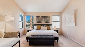 A bedroom with a large bed, a bench, a nightstand, and a lamp. - LAS VEGAS LUXURY HOME, 5 BDRP, POOL W/HEATER, BBQ, GAMES (Las Vegas)