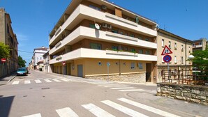 A multi-story building with balconies, a no parking sign, and a pedestrian crossing.