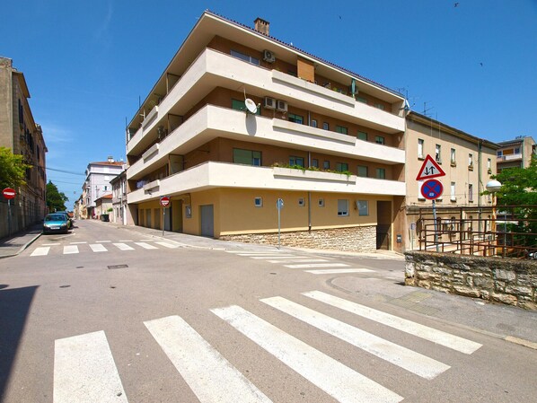 A multi-story building with balconies, a no parking sign, and a pedestrian crossing.