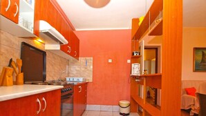 A compact kitchen with wooden cabinets, a stove, and a sink. - Apartment 1142/9868 (Istria - Valbandon), 750m from the beach (Valbandon)