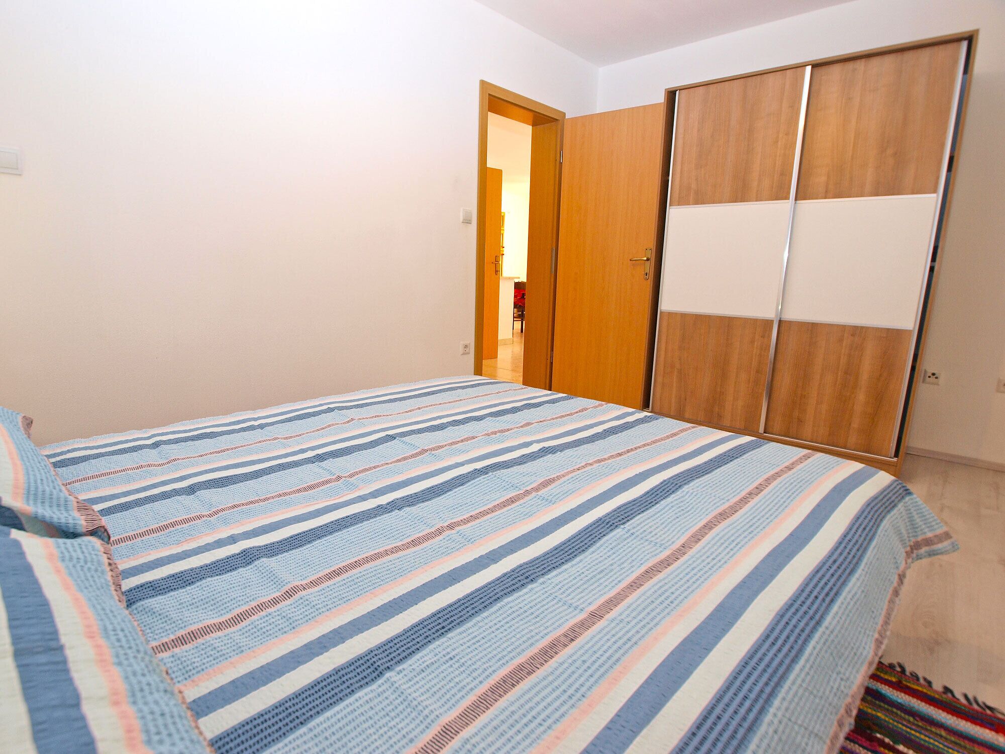 Une chambre à coucher comprenant un lit, une armoire et une porte donnant sur une autre pièce.