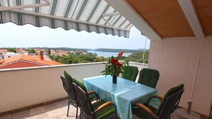 Ein Balkon mit Tisch und Stühlen mit Blick auf eine Küstenstadt.