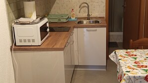 Une cuisine compacte équipée d’un four à micro-ondes, d’un évier et d’une petite table à manger.