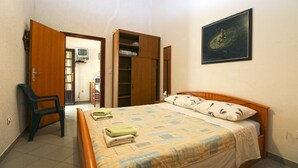 Une chambre à coucher avec un lit, une chaise, une armoire et un téléviseur.
