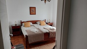 Un lit bien fait, avec une tête de lit en bois, deux tables de chevet avec des lampes, un tableau encadré au mur et un plancher en bois.