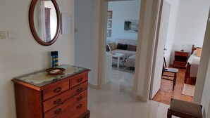 Une chambre d’hôtel avec une commode en bois, un miroir et un lit recouvert d’une couvre-lit à rayures.
