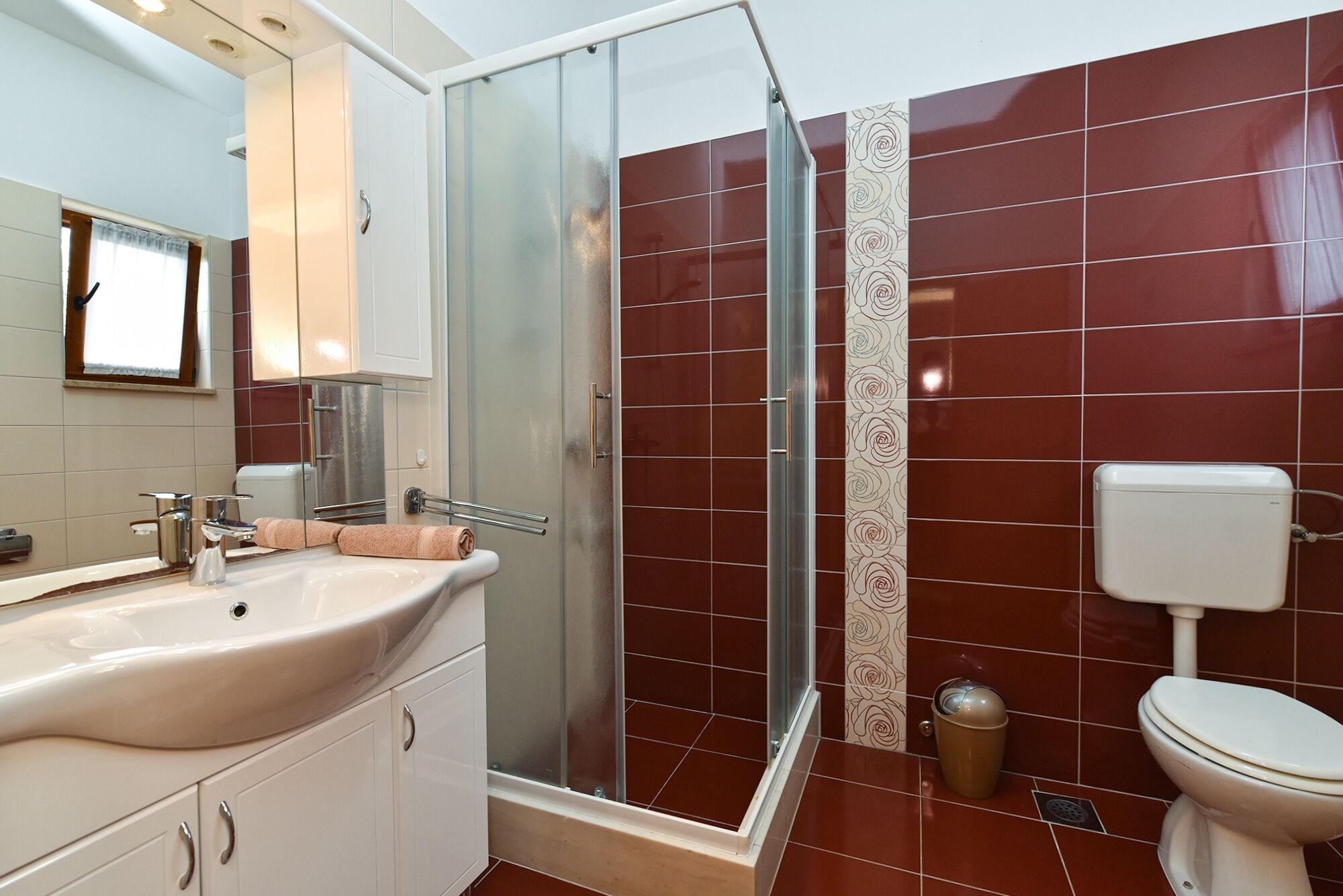 A bathroom with a glass shower enclosure, a sink with a mirror, and a toilet.