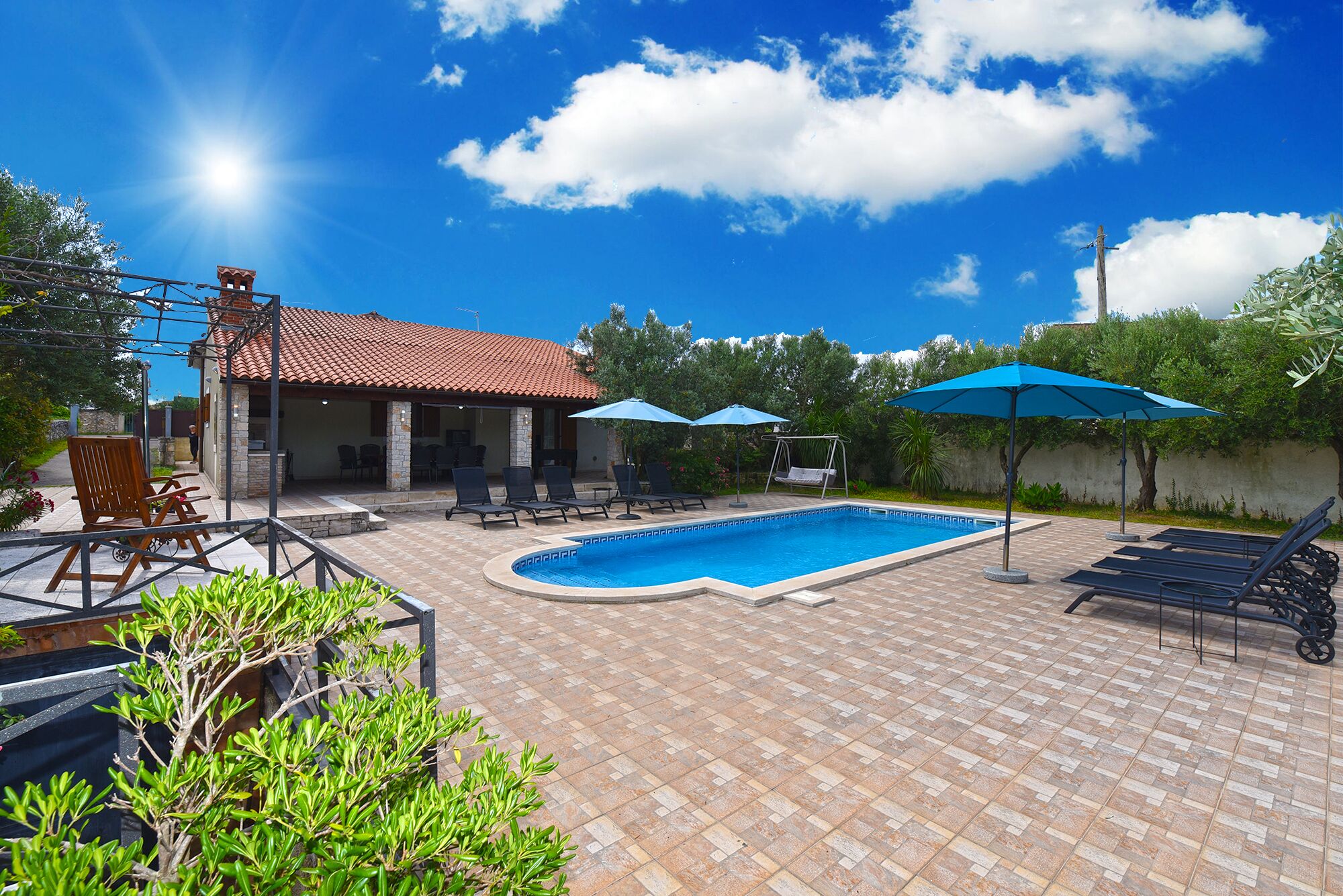 Un patio trasero con piscina, sillas de descanso y sombrillas.