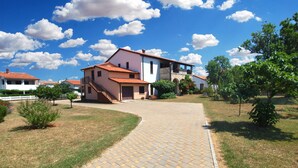 A paved pathway leading to a two-story house with a red-tiled roof, surrounded by greenery and other houses. - Apartment 1189/10858 (Istria - Premantura), 500m from the beach (Premantura)
