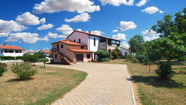 A paved pathway leading to a two-story house with a red-tiled roof, surrounded by greenery and other houses. - Apartment 1189/10860 (Istria - Premantura), 500m from the beach (Premantura)