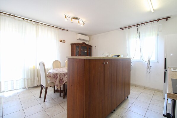 A dining area with a wooden table and chairs, a cabinet, and a refrigerator.