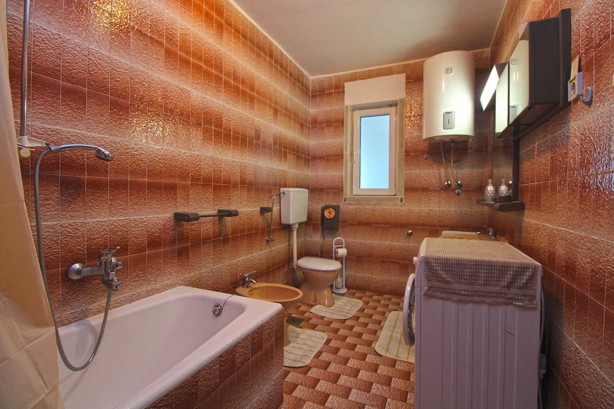 A bathroom with a bathtub, toilet, sink, and a mirror.