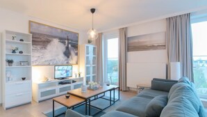 A modern living room with a large sofa, a coffee table, a TV, and a bookshelf. - Pura vida with balcony by Interhome (Bredene)