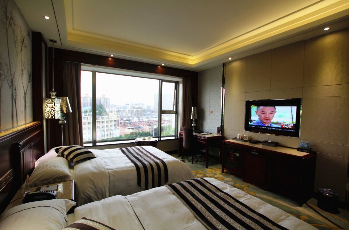 Une chambre d’hôtel avec deux lits, un bureau, une télévision et une vue sur la ville.
