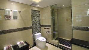 A modern bathroom with a glass shower enclosure, a toilet with a privacy partition, and a tiled backsplash. - Jin Long Wan Hao Hotel (Wuzhou)