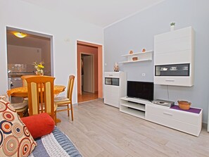 Relax in this stylish living room with a sofa, dining table, and flat-screen TV.