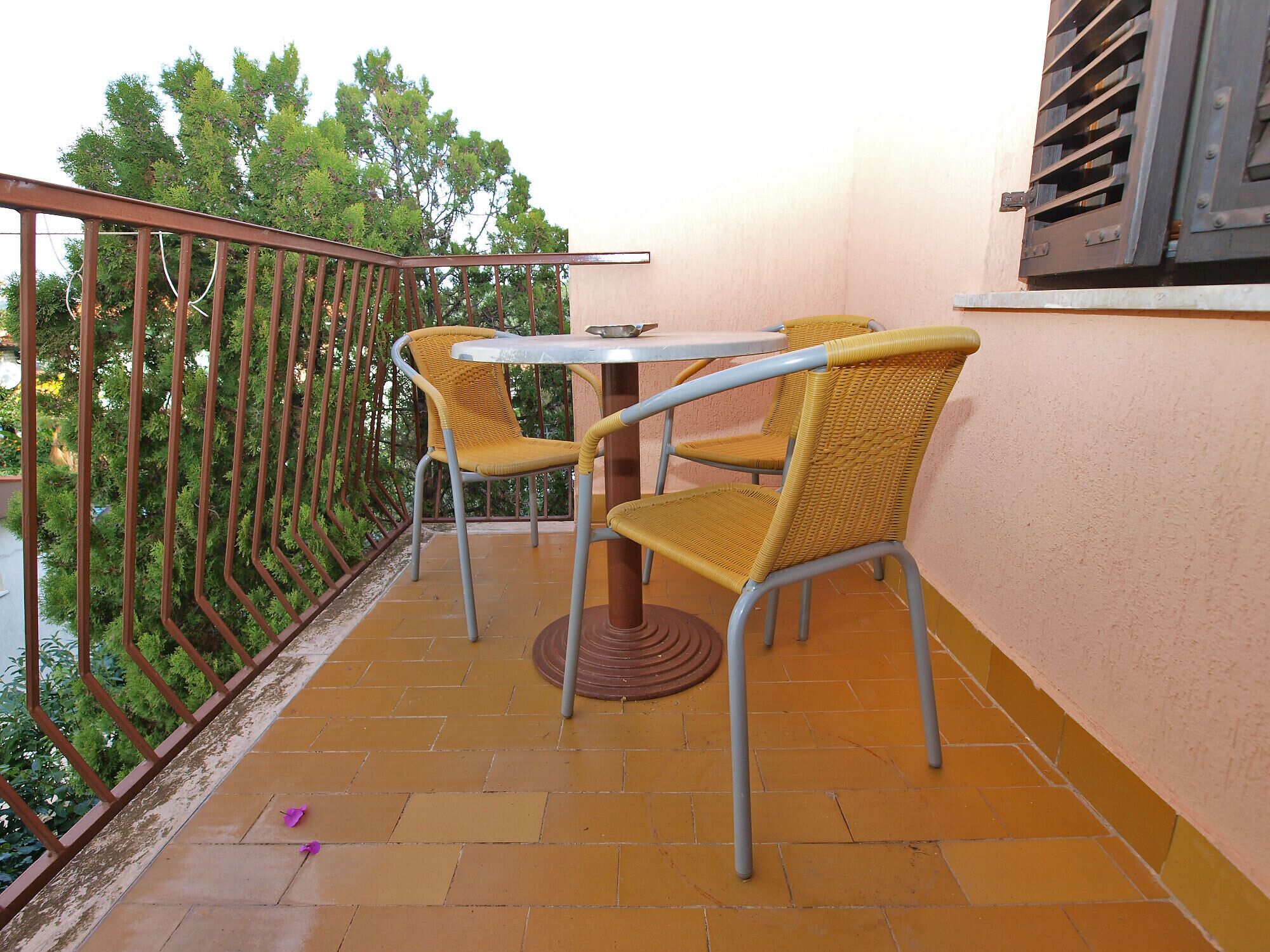 A balcony with two wicker chairs and a small table.