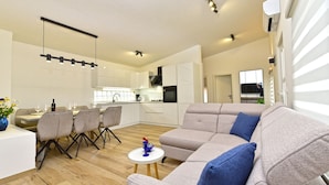 A modern living room with a sofa, dining area, and kitchen.