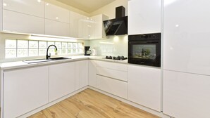 A modern kitchen with white cabinets, a black stove, and a window with a view.