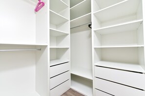 A white closet with multiple shelves and drawers, a hanging rod, and a pink hanger.