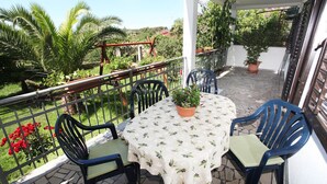 A small outdoor patio with a round table and two chairs, surrounded by a metal railing.