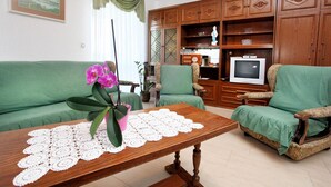 A living room with green sofas, a wooden coffee table, a television, and wooden cabinets.