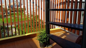 Un balcón con vista a un barrio residencial, baranda de madera y una planta en maceta.