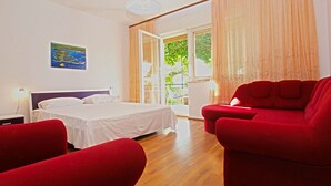 A bedroom with a bed, a red sofa, a red armchair, a nightstand, a lamp, a window with curtains, and a painting on the wall. - House 1214/11158 (Istria - Banjole), 400m from the beach (Banjole)