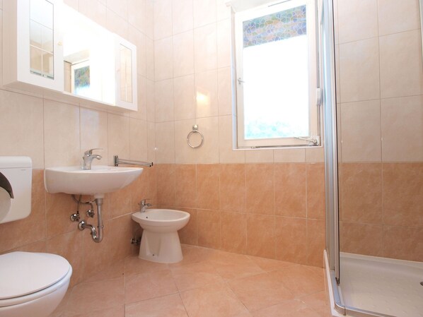 Une salle de bain comprenant des toilettes, un lavabo, un bidet et un espace douche.