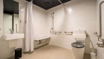 Un baño moderno con inodoro, lavamanos, ducha y espejo.