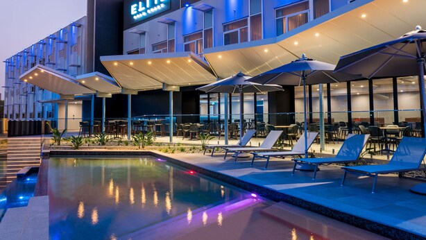 Un hôtel doté d’une piscine, d’un espace extérieur aménagé pour s’asseoir et d’une enseigne sur laquelle on peut lire « ELITE ».