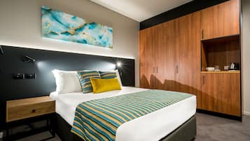 A modern bedroom with a large bed, wooden wardrobe, and a nightstand.