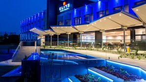Un hôtel moderne doté d’une piscine, d’un espace extérieur aménagé et d’une entrée bien éclairée.
