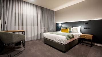 Una habitación de hotel moderna con una cama grande, un escritorio y una silla.