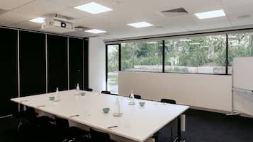 A conference room with a long table, chairs, a projector, and a whiteboard.